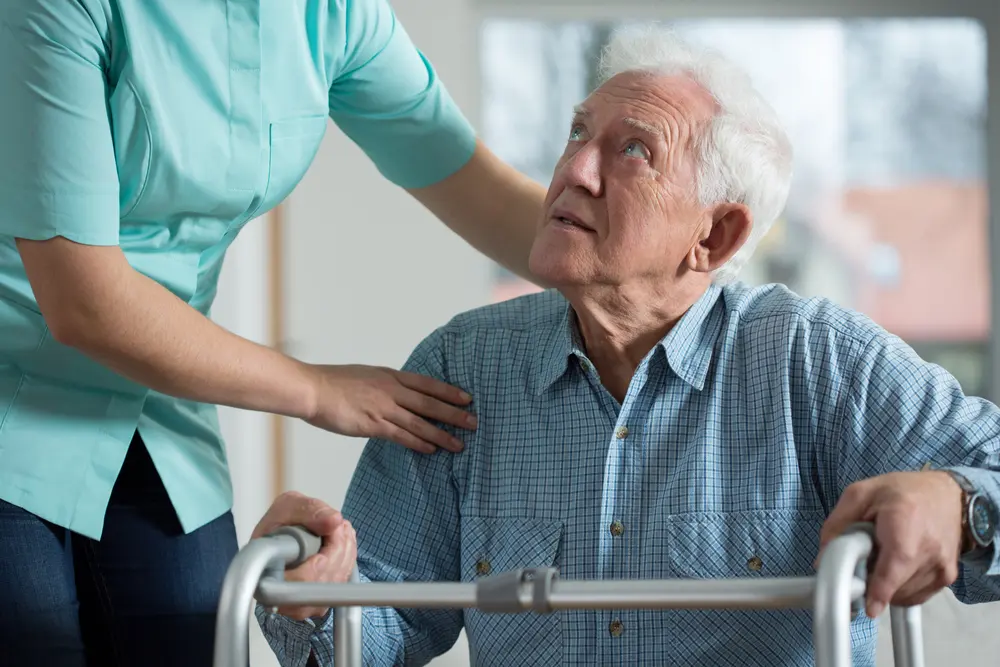 Older man with walker receiving assistance from another person